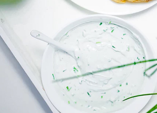 A bowl of tzatziki with a spoon dipped in it.